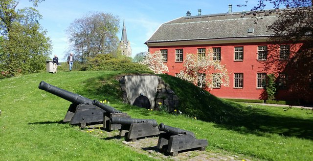 Slottsträdgården vid Halmstads slott med fyra kanoner i förgrunden, två personer skymtar långt bak i bilden.