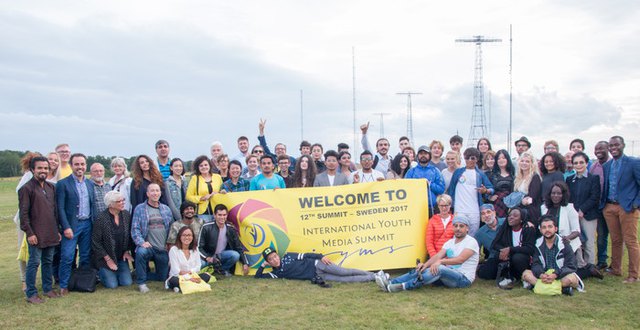 Gruppfoto deltagare i internationellt läger för unga och unga vuxna, framför masterna vid Grimeton Radiostation.