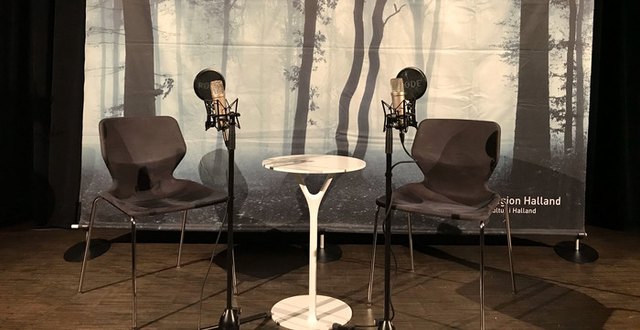 En scen med två stolar och två mikrofoner på varsin sida om ett litet bord.
