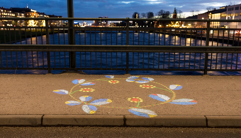 En färgglad broderad blomsterkrans projiceras på gångbanan på Österbro i Halmstad.
