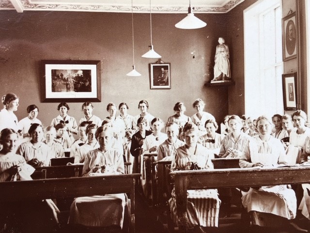 Svartvit äldre bild med unga kvinnor i en lektionssal.