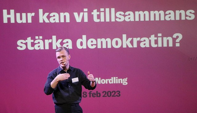 Bild på David Nordling framför skärm med texten Hur kan vi tillsammans stärka demokratin?