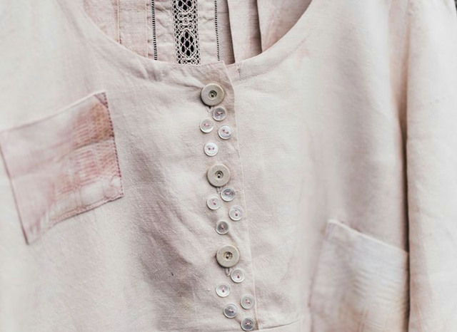 Närbild på en blus eller skjorta med många knappar sydda som dekoration på knappslån.