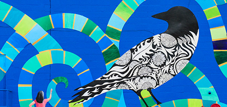 Väggmålning föreställande svartvit fågel med blå spiralmönster bakom.
