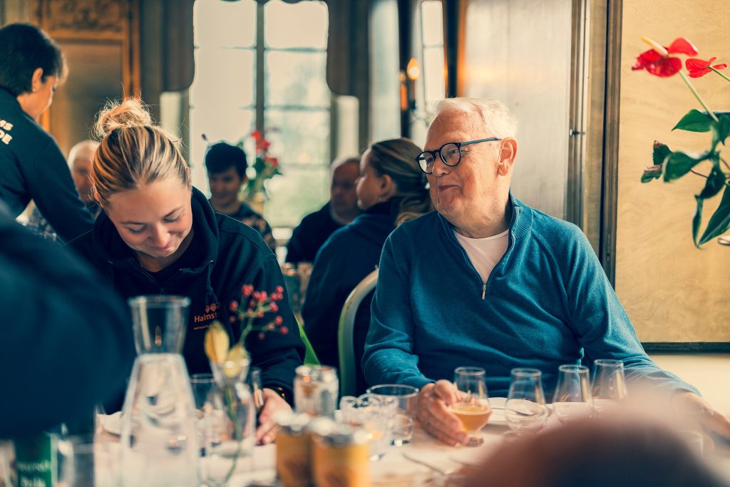 En äldre man och ung kvinna sitter vid matbordet och skrattar