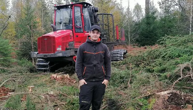 En ung man framför en skogsmaskin i skogen.