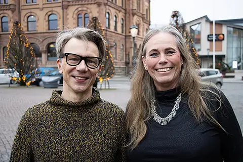 Två personer står utomhus i en stadsmiljö.