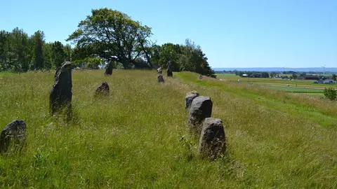 Resta stenar från äldre järnålder och utsikt mot havet vid horisonten.